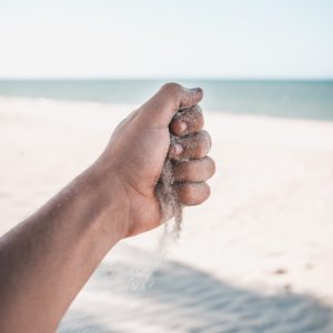 Hand Holding Sand on Beach